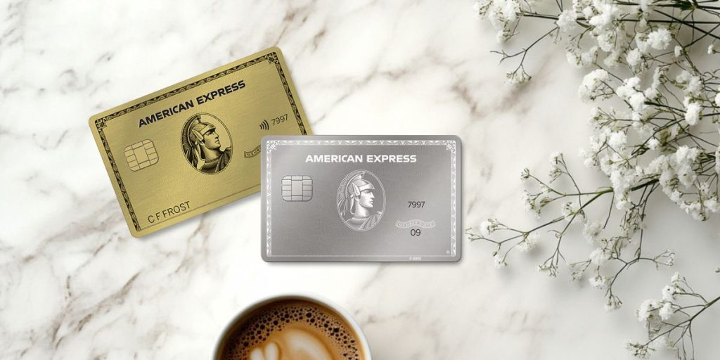 American Express Platinum and Gold cards on a table with coffee and greenery