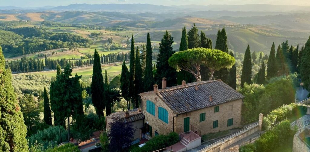 Tuscany, Italy with a home in the foreground and rolling hills in the background.